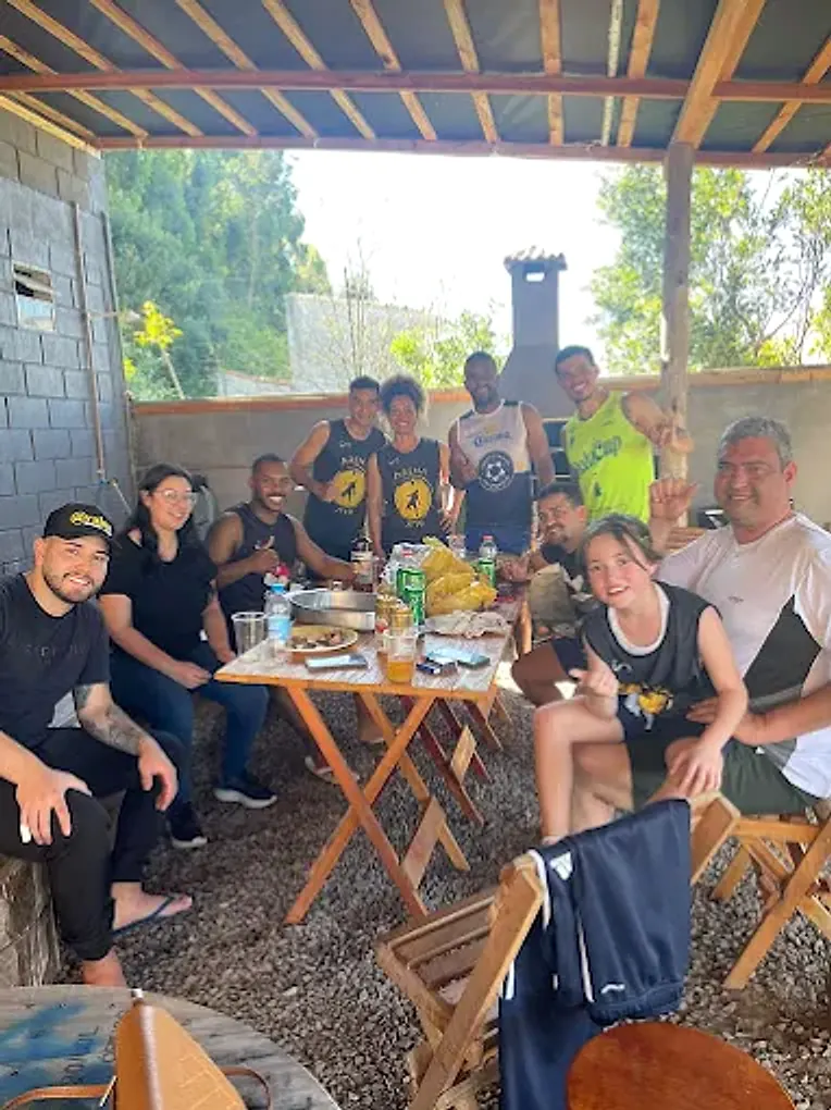 Galera reunida em volta da mesa ao lado da churrasqueira depois do jogo