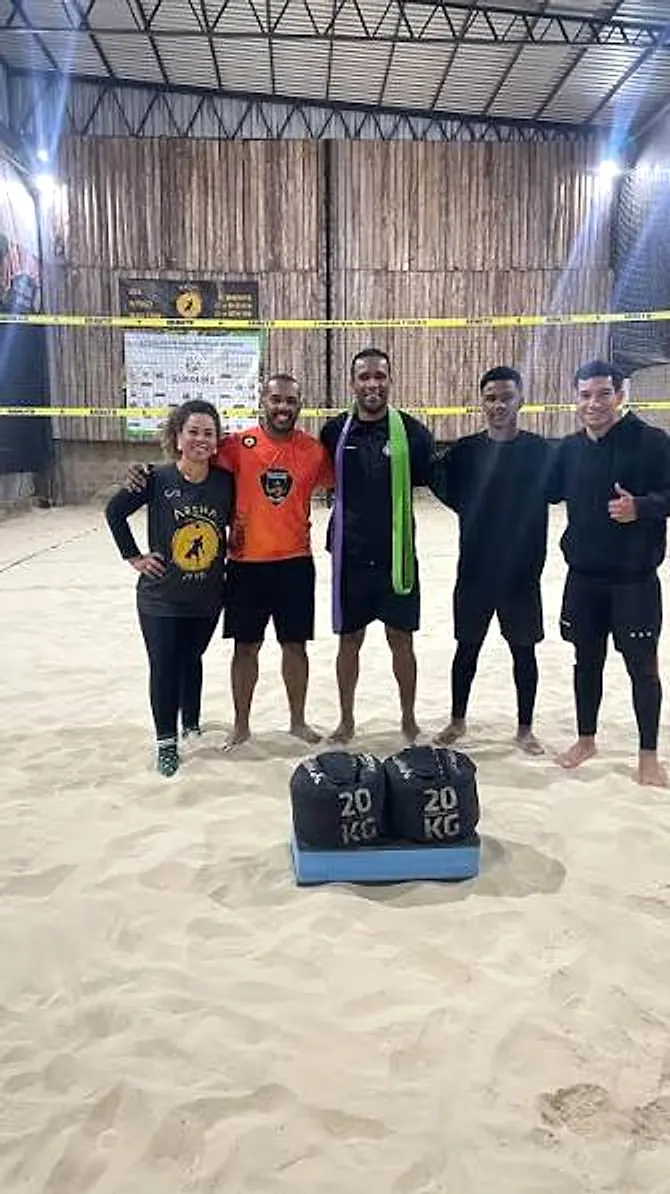 Grupo depois do treino na areia, com os sacos de 20 kg usados no exercício